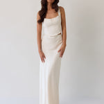 This is the Conrad Set in Ivory. This is a two piece satin set with a fitted, corseted top with thick straps and a delicate tie at the bust and a slight basque waist. It comes with a floor length satin column skirt. 