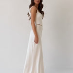 This is the Conrad Set in Ivory. This is a two piece satin set with a fitted, corseted top with thick straps and a delicate tie at the bust and a slight basque waist. It comes with a floor length satin column skirt. 