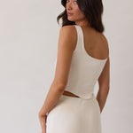 This is the Conrad Set in Ivory. This is a two piece satin set with a fitted, corseted top with thick straps and a delicate tie at the bust and a slight basque waist. It comes with a floor length satin column skirt. 