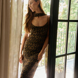 Woman in a leopard print dress standing by a window