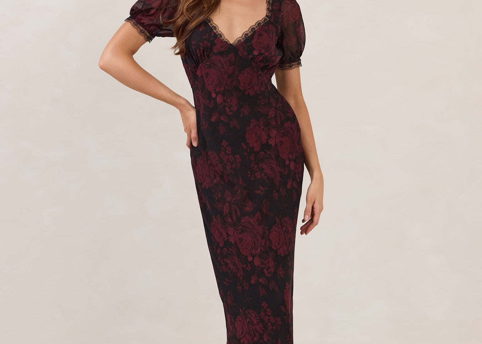 Woman wearing a burgundy floral dress with lace detail on a white background.
