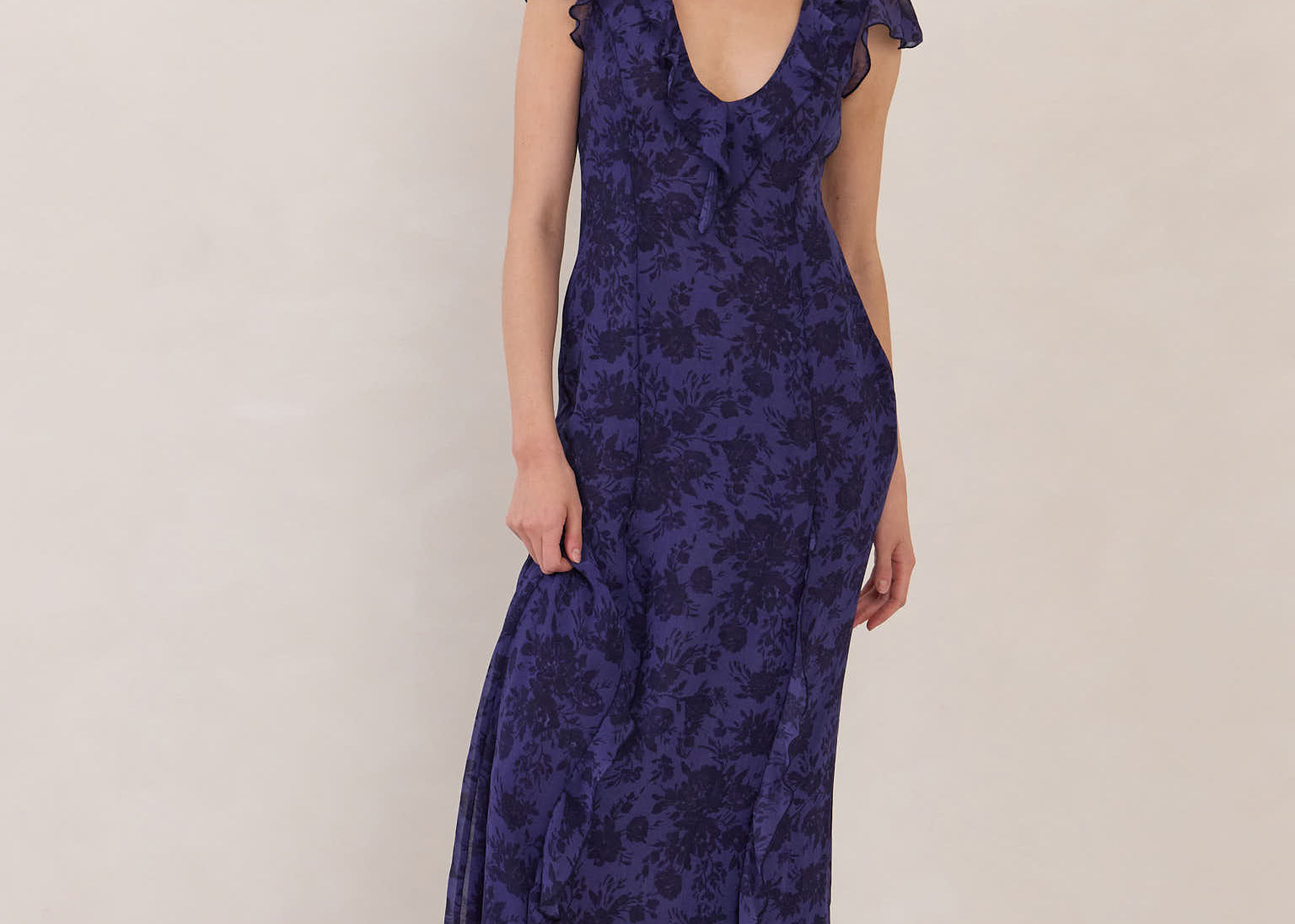 Woman wearing a blue floral dress with a boots and standing against a plain background