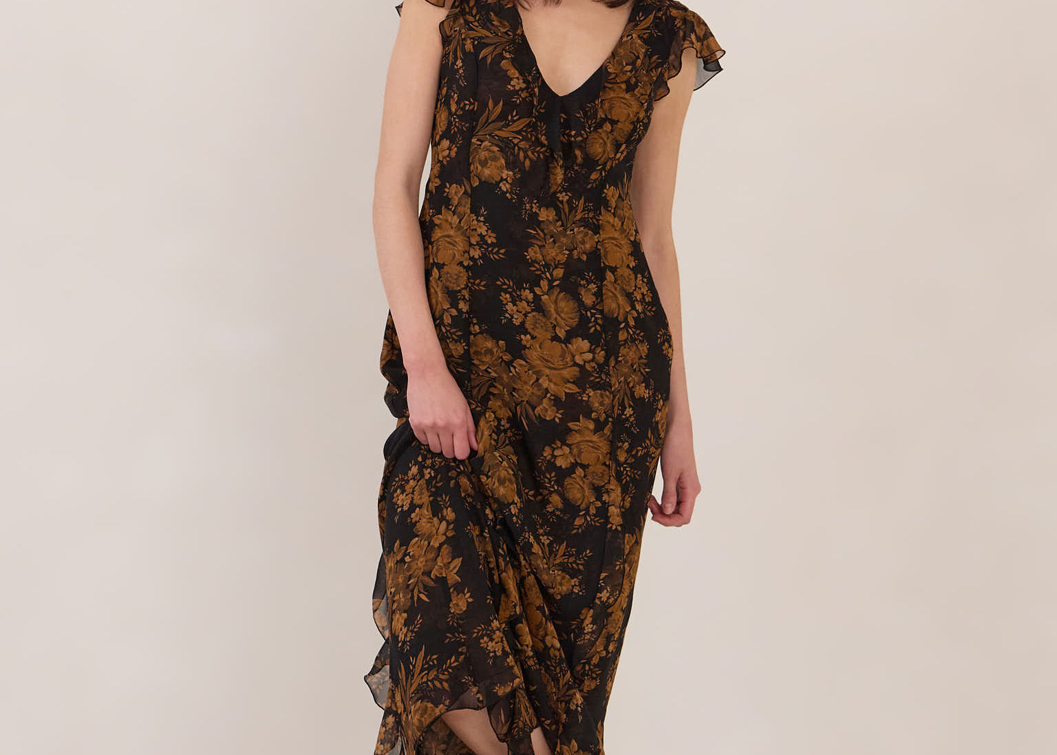 Woman wearing a black and orange floral dress with black boots on a white background