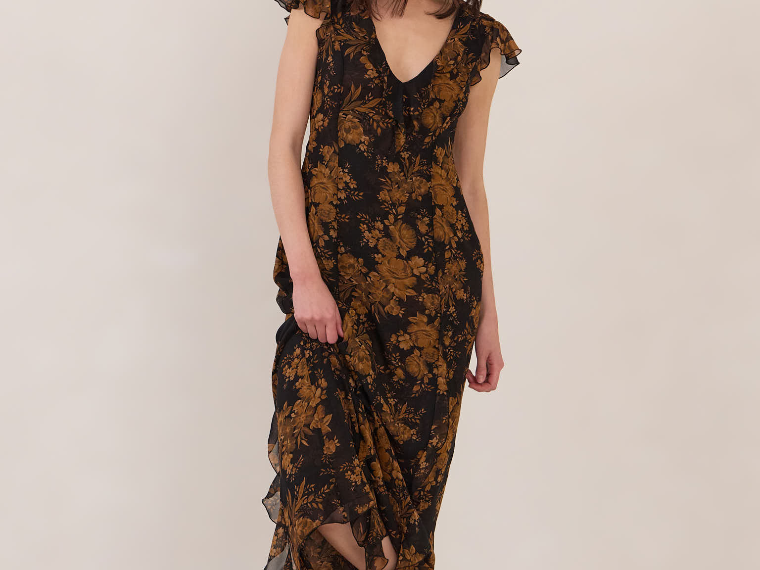 Woman wearing a black and orange floral dress with black boots on a white background