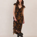 Woman wearing a black and orange floral dress with black boots on a white background