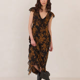 Woman wearing a black and orange floral dress with black boots on a white background