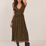 Woman wearing a leopard print dress with black boots on a plain background