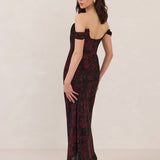 Woman wearing a black and dark red floral off-shoulder gown on a white background