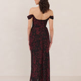 Woman wearing a black and dark red floral off-shoulder gown on a white background