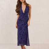 Woman wearing a deep purple floral dress against a plain background