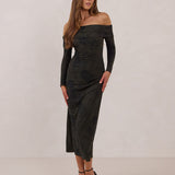 Woman wearing a dark olive floral off the shoulder dress standing against a white background