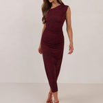 Woman wearing a burgundy floral dress standing against a white background