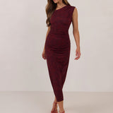 Woman wearing a burgundy floral dress standing against a white background