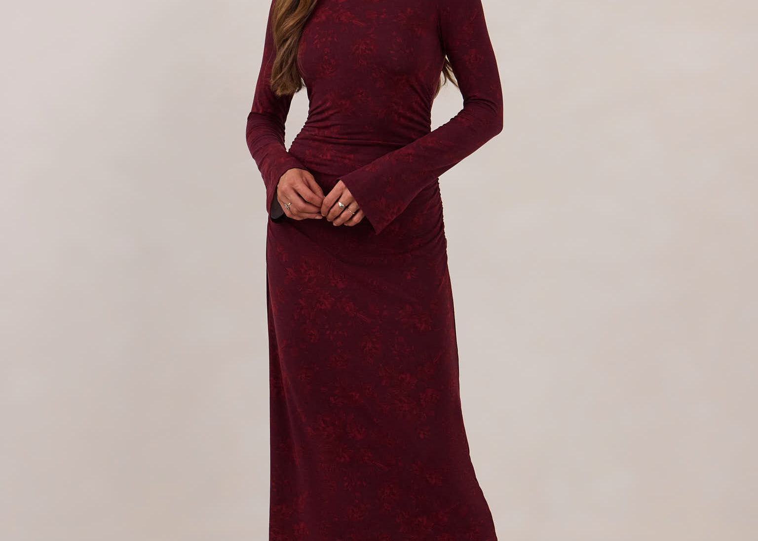 Woman wearing a burgundy dress with long sleeves against a white background
