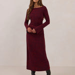 Woman wearing a burgundy dress with long sleeves against a white background