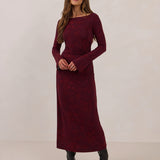 Woman wearing a burgundy dress with long sleeves against a white background