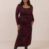 Woman wearing a burgundy floral dress with long sleeves on a beige background
