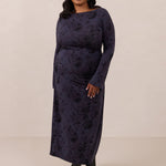 Woman wearing a dark blue patterned dress against a plain background