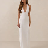 Woman wearing a white halter neck dress against a beige background