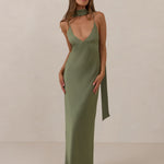 Woman wearing a olive coloured, deep V neck dress against a plain background