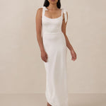 Woman wearing a white sleeveless dress against a beige background