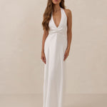 Woman wearing a white halter neck gown against a beige background