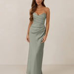 Woman wearing a strapless true sage dress standing against a plain background