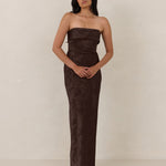 Woman wearing a strapless brown evening gown against a plain background