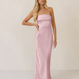Woman wearing a strapless pink evening gown against a plain background