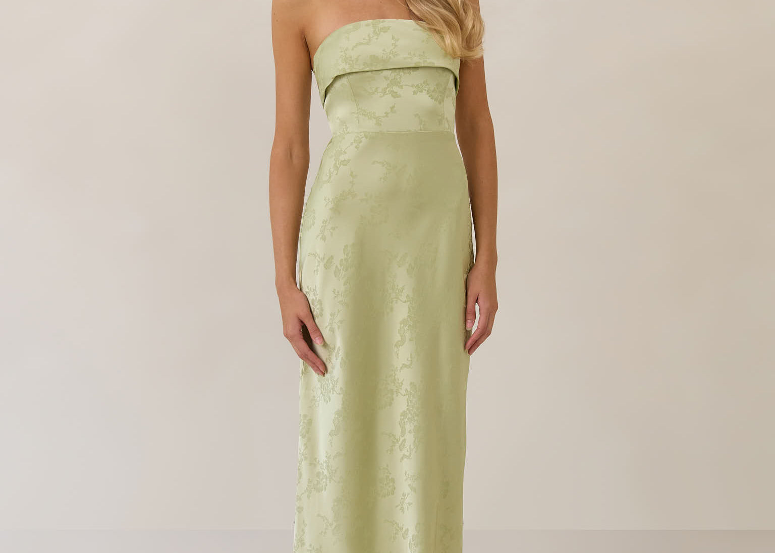 Woman wearing a strapless pistachio dress against a plain background