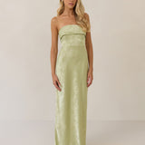 Woman wearing a strapless pistachio dress against a plain background