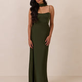 Woman wearing a dark olive coloured evening gown against a beige background