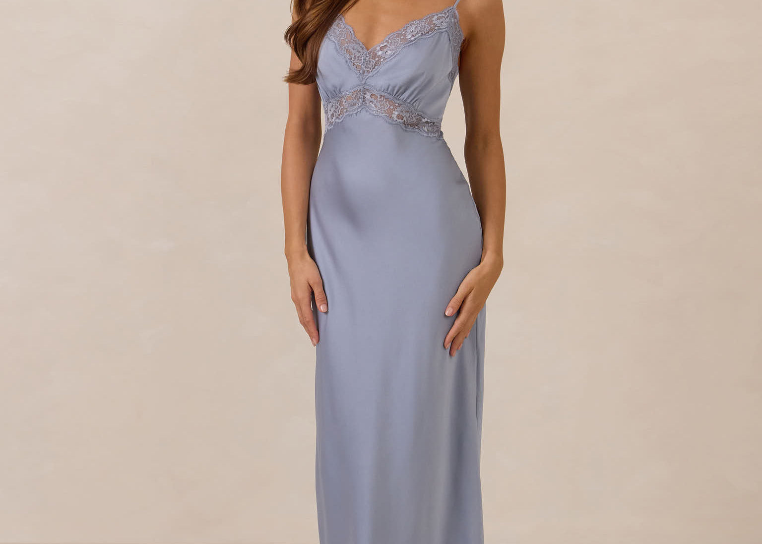 Woman wearing a light blue evening gown with lace detailing on a beige background