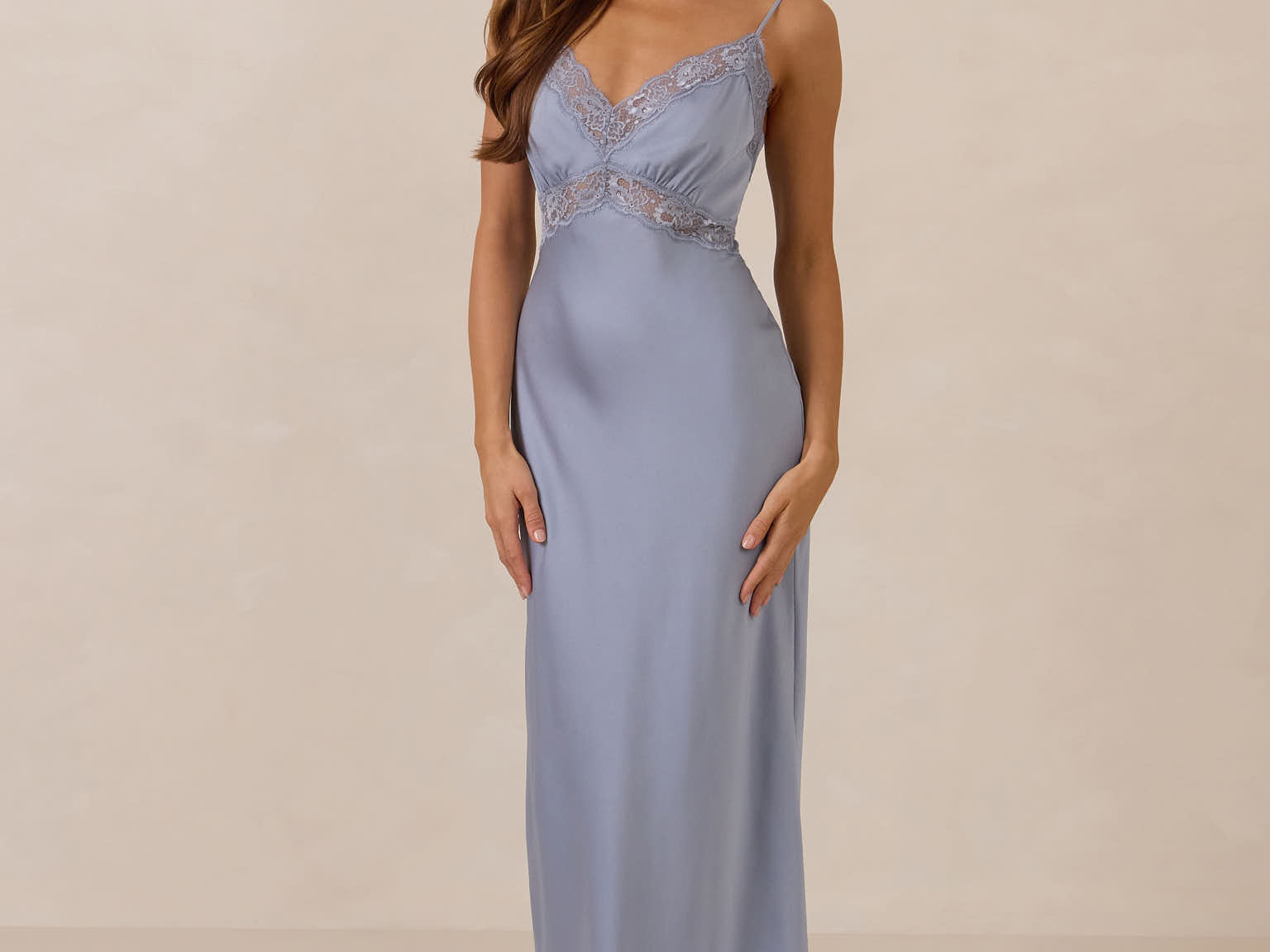 Woman wearing a light blue evening gown with lace detailing on a beige background