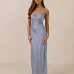 Woman wearing a light blue evening gown with lace detailing on a beige background