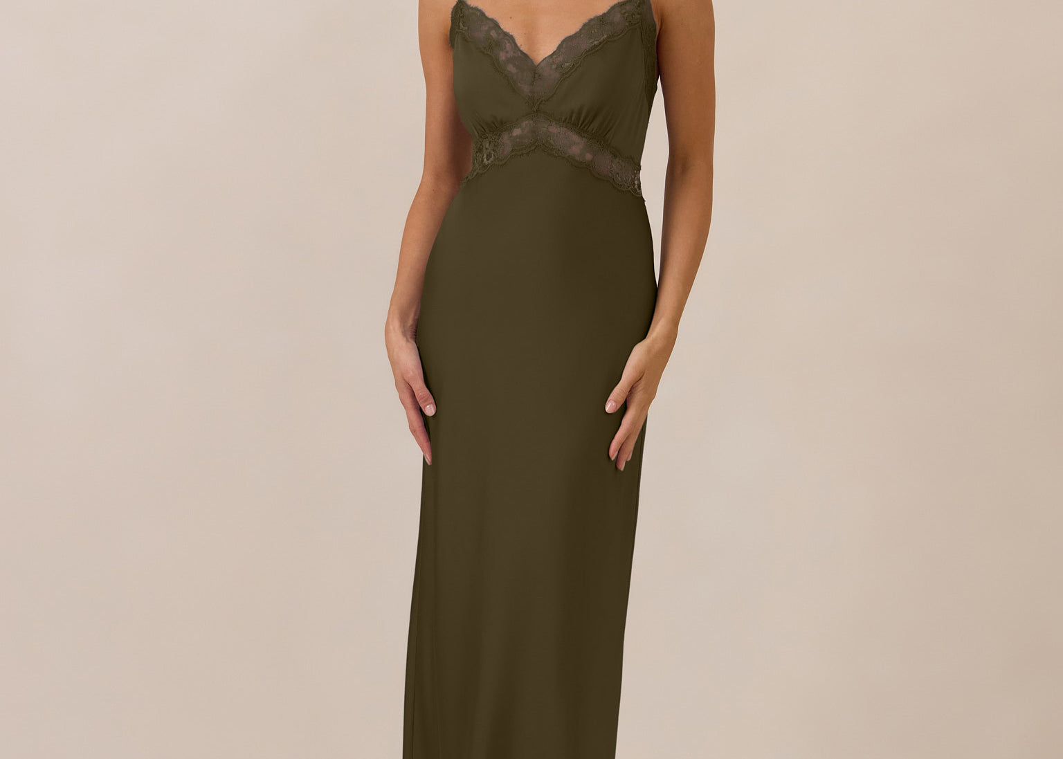 Woman wearing a green evening gown with lace detailing on a beige background