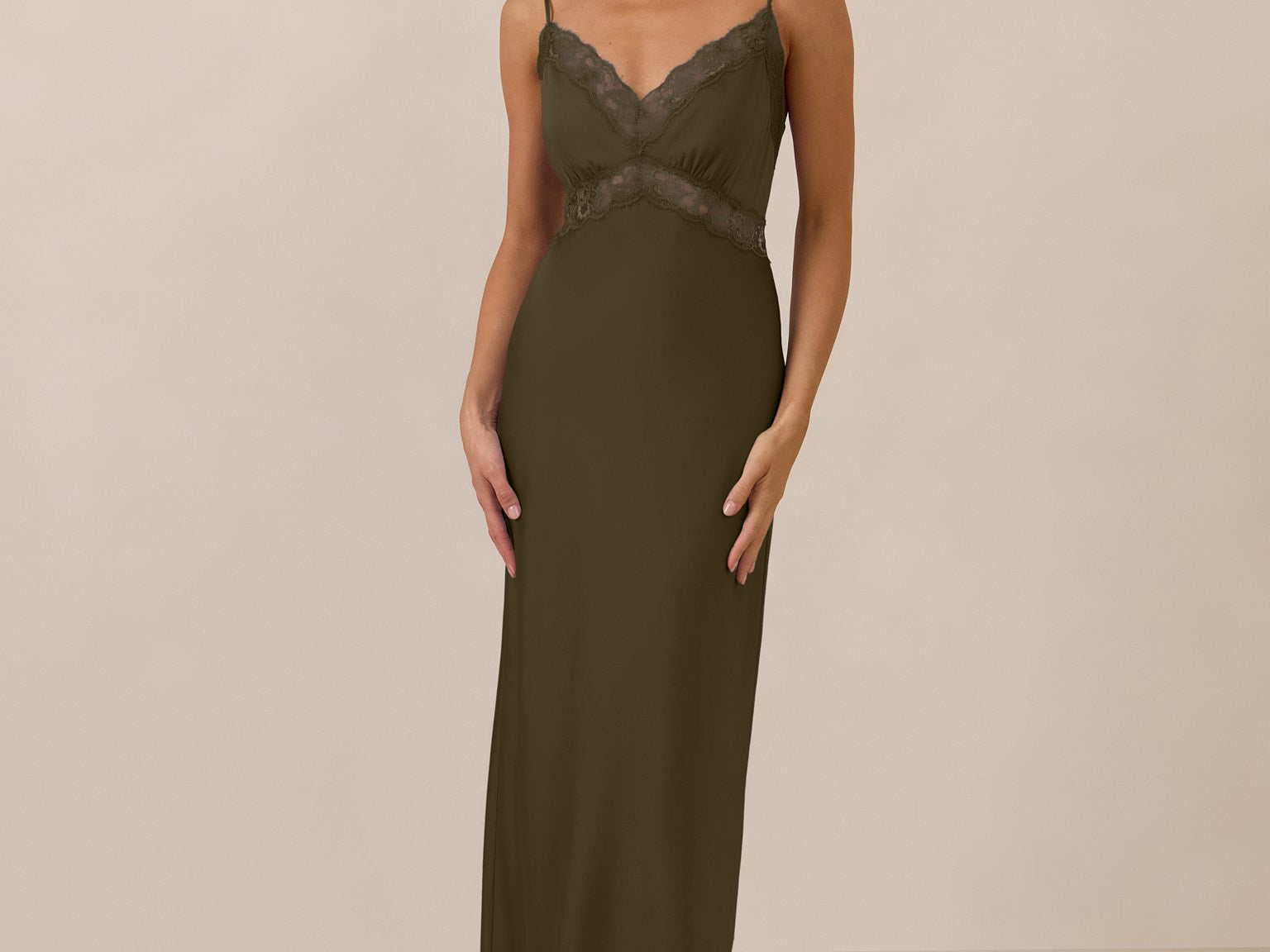 Woman wearing a green evening gown with lace detailing on a beige background