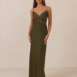 Woman wearing a green evening gown with lace detailing on a beige background