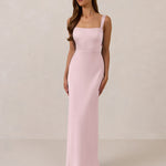 Woman wearing a long light pink dress against a plain background