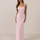 Woman wearing a long light pink dress against a plain background