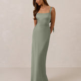 Woman wearing a long true sage dress against a plain background