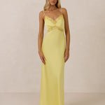 Woman wearing a yellow evening gown with lace detailing on a beige background