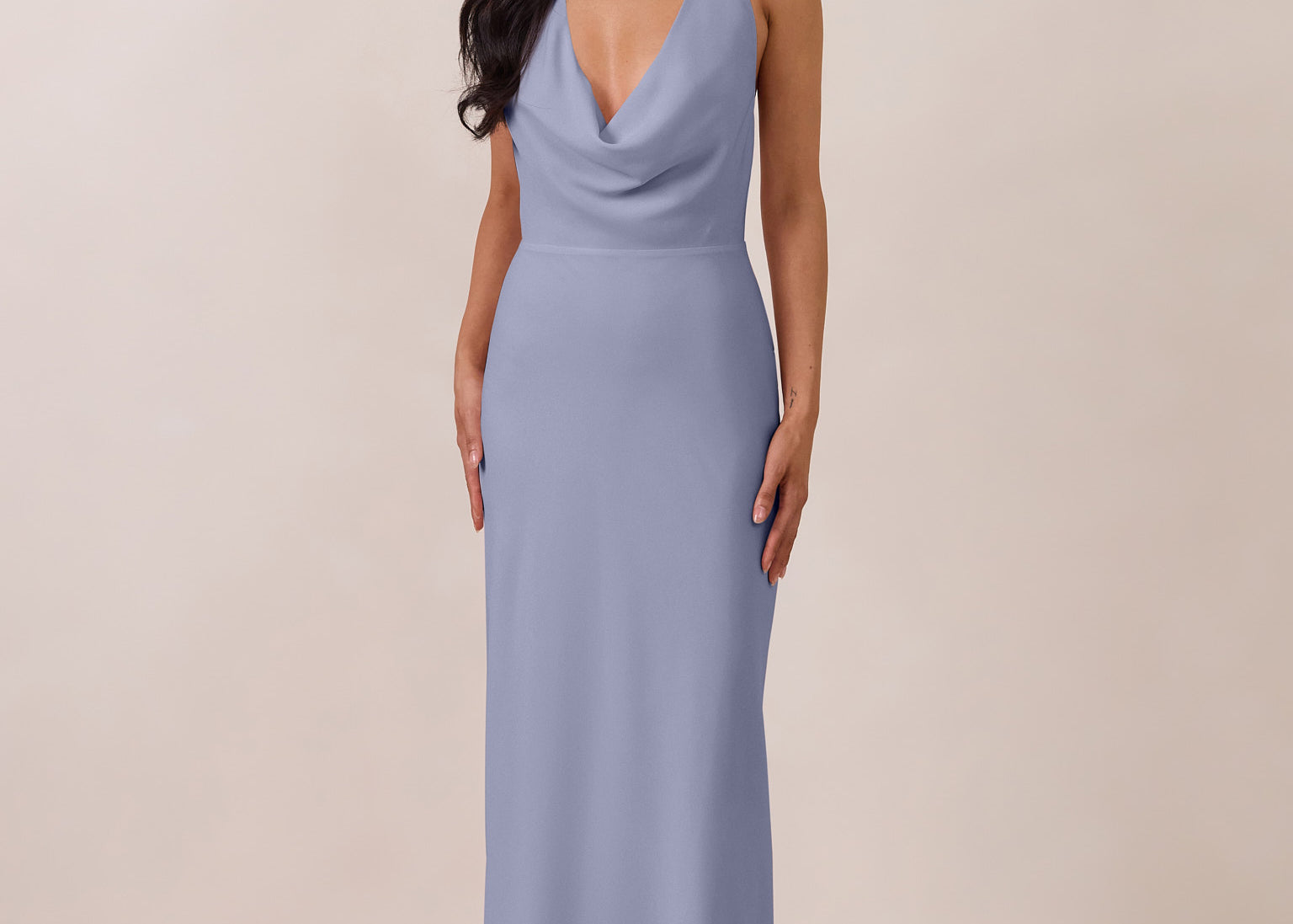 Woman wearing a long, halter style light blue dress against a plain background