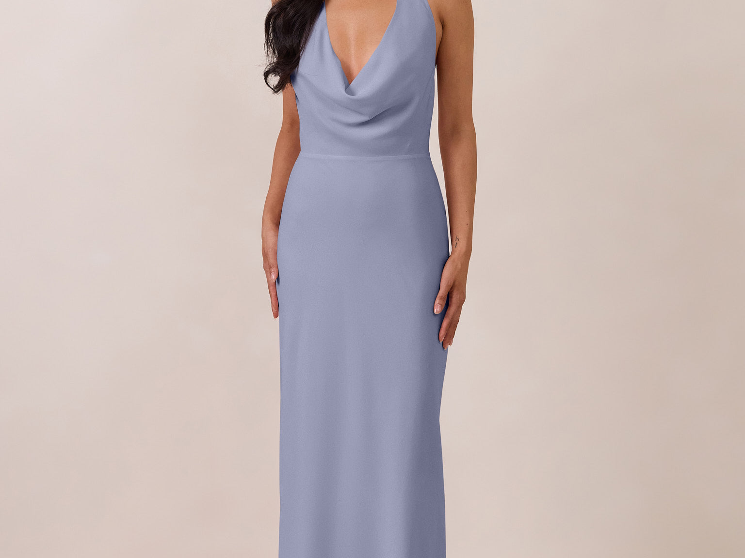 Woman wearing a long, halter style light blue dress against a plain background