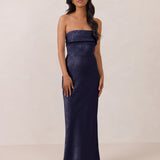 Woman wearing a strapless navy gown against a plain background