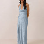 Woman wearing a light blue evening gown against a plain background