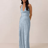 Woman wearing a light blue evening gown against a plain background