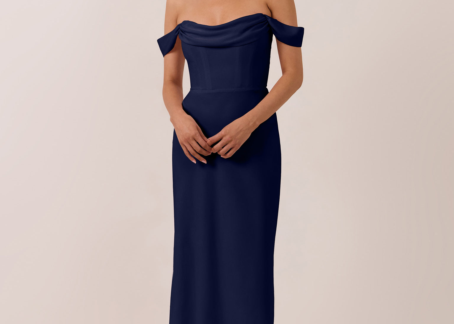 Woman wearing a navy off-shoulder mid length dress against a plain background
