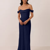 Woman wearing a navy off-shoulder mid length dress against a plain background