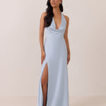 Woman wearing a light blue evening gown with a high slit on a beige background